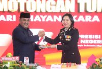 Bupati Karimun Aunur Rafiq menyerahkan potongan tumpeng kepada Wakapolres Karimun Kompol Petra Tumengkol.dalam kegiatan syukuran Hari Bhayangkara ke-77. Foto: Istimewa