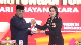 Bupati Karimun Aunur Rafiq menyerahkan potongan tumpeng kepada Wakapolres Karimun Kompol Petra Tumengkol.dalam kegiatan syukuran Hari Bhayangkara ke-77. Foto: Istimewa