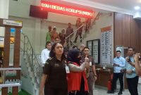 Bendahara KONI Karimun berinisial R mengacungkan jempol kepada wartawan saat digiring menuju mobil tahanan. Foto: KepriHeadline.id