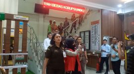 Bendahara KONI Karimun berinisial R mengacungkan jempol kepada wartawan saat digiring menuju mobil tahanan. Foto: KepriHeadline.id
