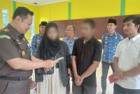 Kajari Karimun Priyambudi menyerahkan buku nikah kepada korban KDRT, setelah perkaranya selesai melalui Restorative Justice. (Foto: ricky/kepriheadline.id)