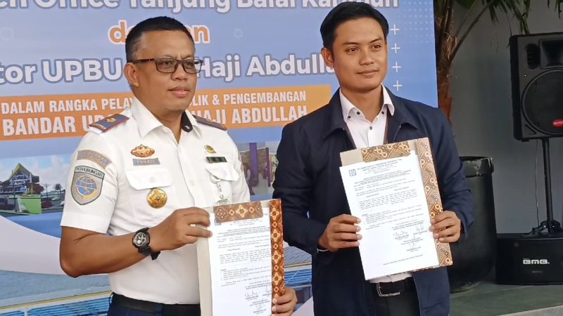 Kepala Bandara RHA Karimun Fanani Zuhri (Kiri) Pimpinan BRI Branch Office Tanjungbalai Karimun Yosi William Kore (Kanan) menunjukkan berita acara kerjasama antara Bandara RHA Karimun dam Bank BRI di bidang Layanan Publik dan Pengembangan Bandara.