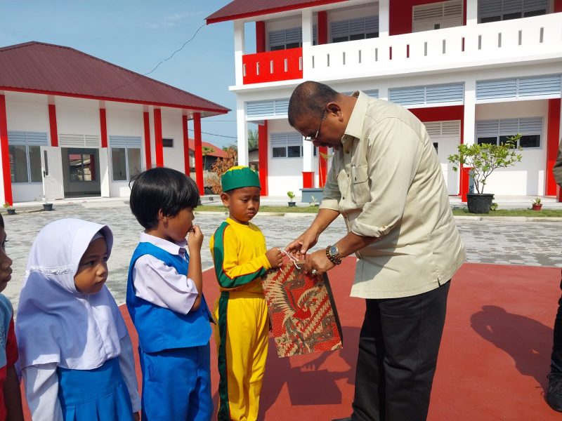 Bupati Karimun Aunur Rafiq menyerahkan swcara simbolis bantuan seragam sekolah gratis kepasa siswa SDN 006 Meral. (Foto: Humas Pemkab Karimun)
