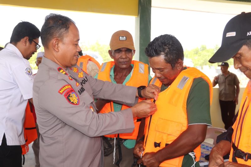 Kasat Polairud Polres Karimun IPTu Sarianto memakaikan secara simbolis life jacket kepadanelayan. Foto: istimewa