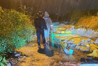 Personil Polsek Tebing membersihkan reruntuhan pagar TPU yang longsor akibat hujan deras. Foto: Istimewa