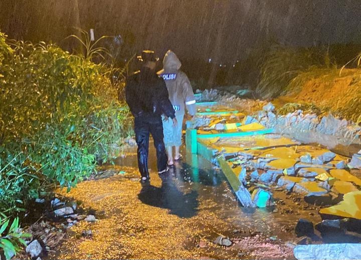 Personil Polsek Tebing membersihkan reruntuhan pagar TPU yang longsor akibat hujan deras. Foto: Istimewa